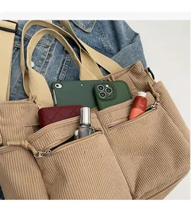 Détail du sac cabas en velours côtelé kaki montrant sa grande capacité et ses poches zippées