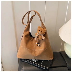Dettaglio borsa Hobo in pelle scamosciata marrone con cuciture e ciondolo orso