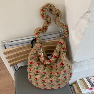 Detail of floral sherpa hobo bag featuring red flower prints and ruffled strap texture