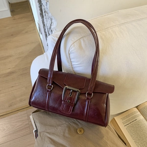Detail of burgundy vintage underarm bag with double straps and large silver metal buckle