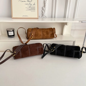 Detail of vintage suede barrel bags in brown and black with contrast stitching
