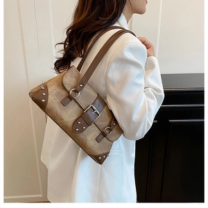Detailed shot of retro brown shoulder bag with silver studs and metal buckle decor