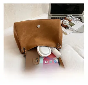 Internal storage detail of brown faux suede tote bag showing tablet and cosmetics