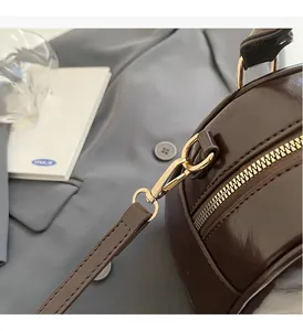 Detailed macro view of dark brown glossy patent leather bag and gold hardware accents