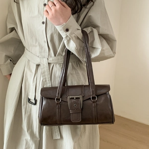 Detail of vintage brown square handbag with large metal buckle held by a model