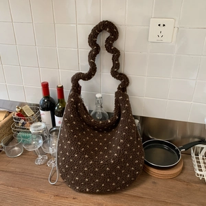 Detail of fuzzy brown tote with white polka dots, wavy handle and metal chain strap