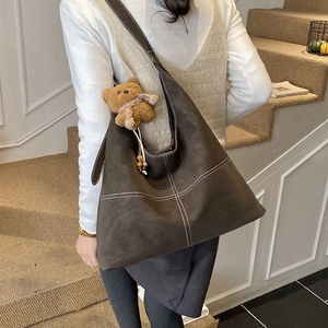 Dettaglio di una grande borsa tote marrone con cuciture bianche a contrasto e charm