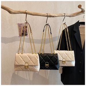 Detail of quilted leather handbag featuring a gold oval twist lock and metal chain strap