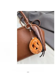 Detail der dunkelbraunen Leder-Bowlingtasche mit Plüsch-Brezel-Anhänger und Logo-Prägung