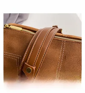 Detail shot of brown matte suede texture and stitching on cylindrical shoulder bag
