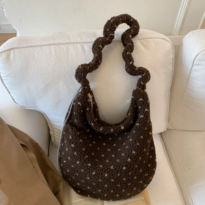 Detailed close-up of brown fuzzy tote bag with white heart patterns and ruffled shoulder strap