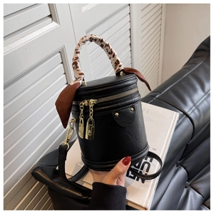 Détail du sac cylindrique noir avec poignée en foulard léopard et dorures élégantes