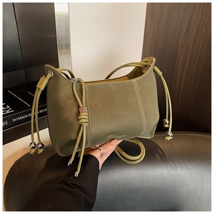 Detail of olive green matte leather shoulder bag with drawstring folds and silver ball charm