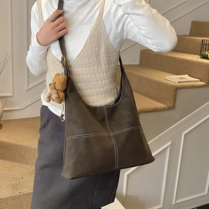 Dettaglio della borsa shopper marrone scuro con cuciture a croce e ciondolo orso