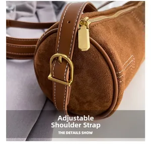 Detail view of the adjustable leather strap and gold-tone metal buckle on a suede bag