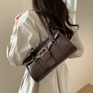 Close-up of retro dark brown shoulder bag featuring oversized silver metal buckle accents