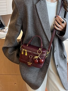Vintage burgundy quilted box bag with gold hardware and cherry charm in a main side view