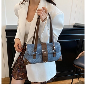 Detail of vintage blue denim shoulder bag with brown leather straps and rivet accents