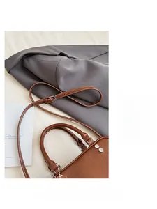 Detail einer braunen Vintage-Ledertasche mit feinen Nähten und verstellbarer Metallschnalle