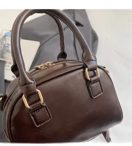 Close-up of retro brown pillow bag with smooth oil wax texture and golden hardware