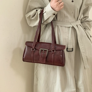 Detail of vintage burgundy leather handbag with large metal buckle on beige coat