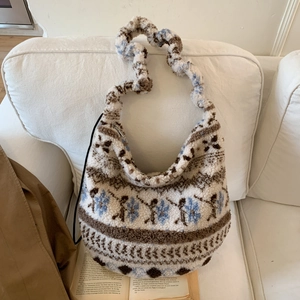 Close-up of fluffy white sherpa tote bag with ethnic jacquard patterns on a sofa