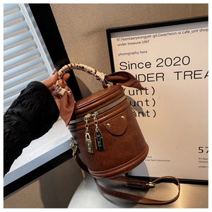 Close-up of vintage brown cylinder bucket bag with lychee texture and silk scarf handle
