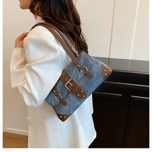 Detail of vintage denim shoulder bag with brown leather trim and silver metal studs
