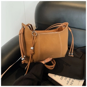 Detailed view of caramel brown bucket bag with silver ball charms and drawstring texture