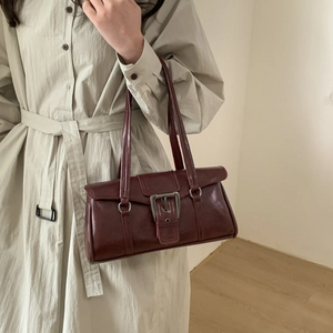 Detail of burgundy vintage rectangle shoulder bag with metallic buckle and leather texture