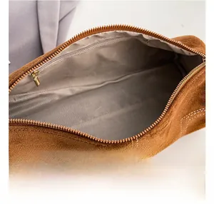Macro shot of brown suede bag showing zipper opening and herringbone fabric lining