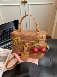 Vintage brown leather box bag with quilted stitching and cherry charm in office setting