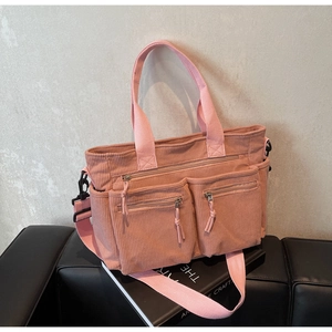 Détail du sac fourre-tout en velours rose avec poches zippées et texture nervurée