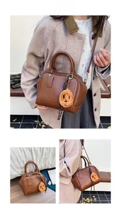 Detail der braunen Retro-Bowlingtasche mit orangefarbenem Brezel-Plüsch-Anhänger