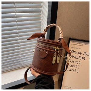 Detail of vintage brown bucket bag with leopard scarf handle and golden hardware in sunlight