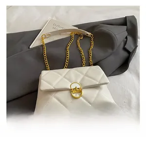 Close-up of white quilted chain bag featuring a gold twist lock on a textured blazer