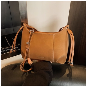 Detail of caramel faux leather shoulder bag featuring drawstring tassels with silver metal beads