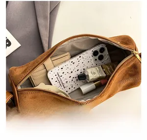 Interior view of brown suede cylinder bag showing large capacity for phone and cosmetics