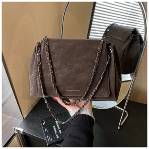 Detail of dark brown matte chain bag with vintage industrial finish reflected in a mirror