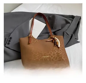 Détail du sac cabas vintage embossé léopard avec accessoire en perles sur blazer gris