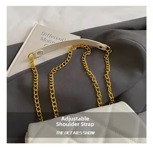 Detail view of the adjustable white quilted bag strap with golden chain and leather pad