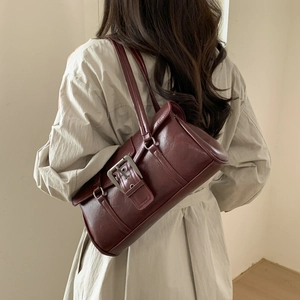 Detail showing deep red retro leather handbag with silver buckle on beige coat