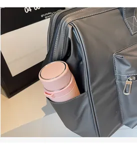 Détail de la poche latérale d'un sac de voyage gris avec une gourde rose pour rangement