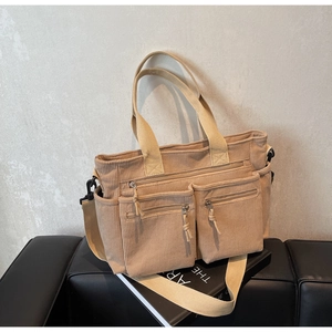Détail d'un sac cabas en velours côtelé avec poches zippées et poignées tissées