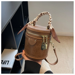 Detail of vintage brown cylinder bucket bag with cow print silk scarf and gold hardware