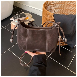 Detail of dark brown leather bag with white contrast stitching and silver logo print