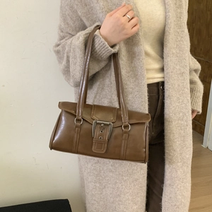 Close-up of vintage brown leather handbag with metal buckle detail and dual handle design