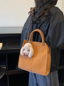 Brown rectangular leather tote bag with a plush bunny charm and detachable strap