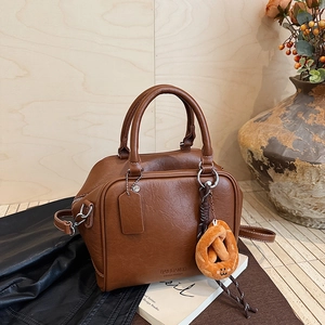 Detailansicht einer Vintage dunkelbraunen Leder-Boston-Tasche mit flauschigem Brezel-Anhänger
