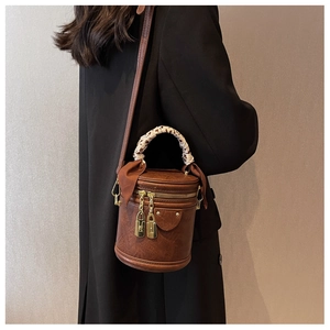 Detail of dark brown bucket bag with leopard scarf handle and gold hardware on model